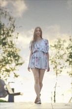 Young woman walking along park alley in the evening