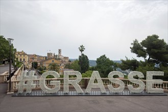 Lettering #Grasse, behind it the building of the perfume manufacturer Fragonard, Grasse,