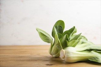 Fresh green bok choy or pac choi chinese cabbage on a brown wooden background. Side view, copy