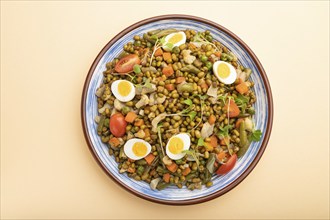 Mung bean porridge with quail eggs, tomatoes and microgreen sprouts on a pastel orange background.