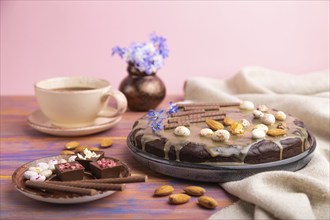 Homemade chocolate brownie cake with caramel cream and almonds with cup of coffee on a colored and