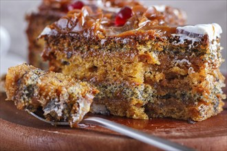 A piece of cake with caramel cream cutted with spoon on a wooden kitchen board and a cup of coffee,