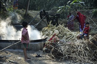 Workers boiling sugarcane juice as they are making Gur (jaggery) in a village on December 10, 2021