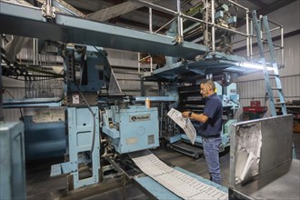 Liberal, Kansas, Danny Moura checks papers coming off the printing press at the Leader & Times.