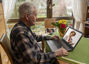 Symbolic image of telemedicine, elderly patient speaking to a doctor in a video conference from