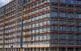 Large construction site, scaffolded shell of an office building complex, air hoses for building