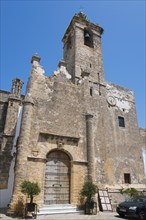 Historic church with high tower, massive entrance and stony walls under a clear sky, Iglesia del