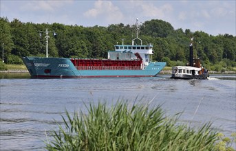 Steam tug Woltman and cargo ship Fredo sailing in the Kiel Canal, Schleswig-Holstein, Germany,