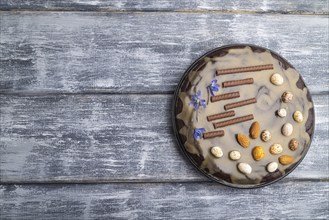 Homemade chocolate brownie cake with caramel cream and almonds on a gray wooden background. top