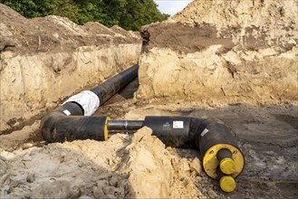 Laying of district heating pipes, next to a field, with maize, the district heating comes from a