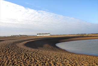 Frontal clouds passing over Coastguard Cottages shingle beach at Shingle Street, Suffolk, England,