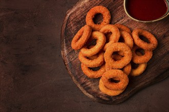 Crispy chicken rings, fried, on a wooden board, close-up