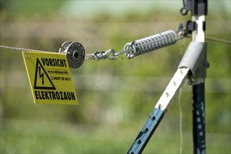 Electric fence on a pasture, warning sign, electric shock