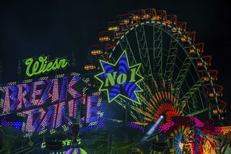 Illuminated ride Break Dance, behind the illuminated Ferris wheel in motion, night shot,