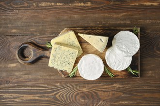 Top view of wooden platter with assortment of cheeses