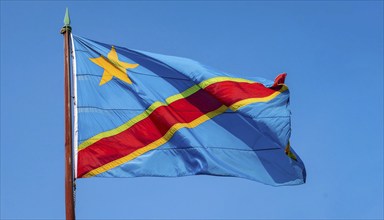 The flag of the Democratic Republic of the Congo flutters in the wind, isolated against a blue sky