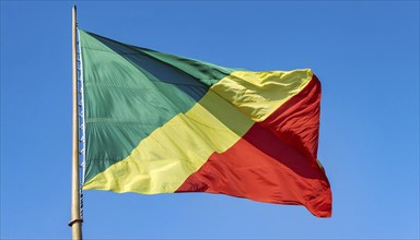 The flag of Congo flutters in the wind, isolated against a blue sky