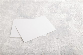 White paper business card, mockup on gray concrete background. Blank, side view, still life, copy