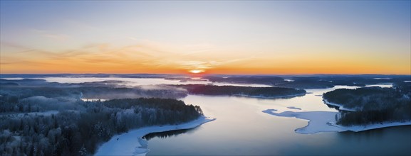 Serene winter landscape at sunrise with snow-covered trees and a frozen lake, AI generated