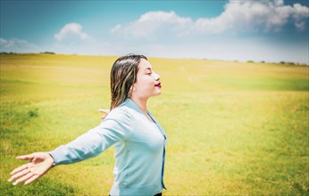 Happy girl spreading arms breathing fresh air in the field. Relaxed woman breathing fresh air in a