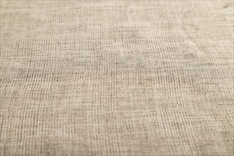 Fragment of smooth brown linen tissue. Side view, natural textile background and texture