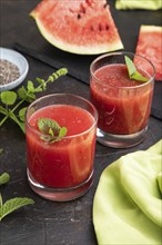 Watermelon juice with chia seeds and mint in glass on a black concrete background with green