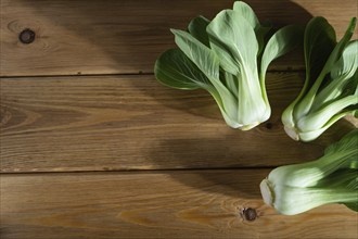 Fresh green bok choy or pac choi chinese cabbage on a brown wooden background. Hard light, contrast