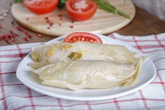 Cabbage rolls with beef, rice and vegetables on a linen tablecloth on a brown wooden background.