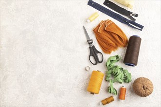 Sewing accessories: scissors, thread, thimbles, braid on gray concrete background. Top view, flat