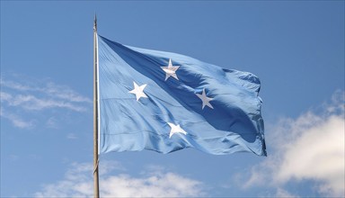 The flag of Micronesia, Pacific Islands, fluttering in the wind, isolated against a blue sky