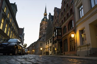 A street illuminated with lanterns in the old town of Stralsund, St.Jakobi church in the