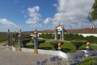 Traditional building in a well-kept garden with hedges and decorative elements under a sky with