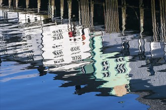 Pier at harbor in Henningsvær, reflections of wooden houses in the calm water, Austvagøy, Lofoten,