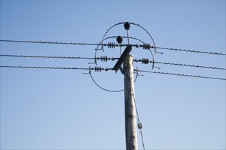 Close up of electricity cables and telegraph pole against blue sky, UK