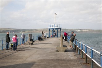 People fishing from harbour breakwater pier at Weymouth, Dorset, England, UK