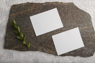 White paper business card, mockup with natural stone and boxwood branch on gray concrete background