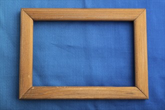 Wooden frame on smooth cotton blue tissue. Top view, flat lay, natural textile background and