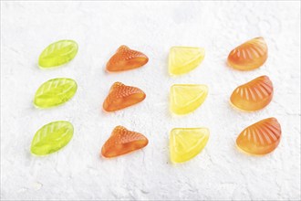 Various fruit jelly candies on gray concrete background. side view, close up