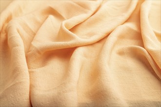 Fragment of orange linen tissue. Side view, natural textile background and texture. wave concept,