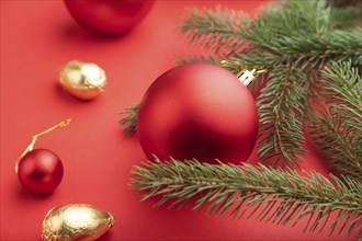 Christmas or New Year composition. Decorations, red balls, fir and spruce branches, on a red paper