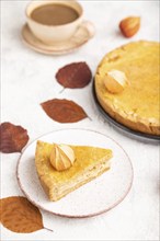 Autumn onion pie decorated with leaves and cup of coffee on gray concrete background. Side view,