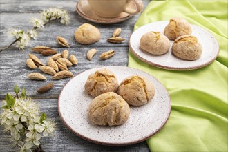 Almond cookies and a cup of coffee on a gray wooden background and green linen textile. Side view,