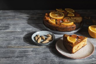 Orange cake on a gray wooden background. Hard light. contrast, low key. Side view, copy space