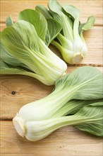 Fresh green bok choy or pac choi chinese cabbage on a brown wooden background. Side view, close up