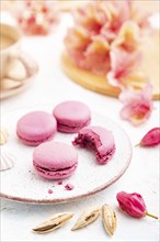 Purple macarons or macaroons cakes with cup of coffee on a white concrete background decorated with