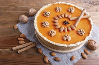 Traditional american sweet pumpkin pie decorated with nuts, on brown wooden background. close up,