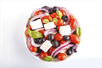 Greek salad with fresh cherry tomatoes, feta cheese, black olives, basil and onion isolated on