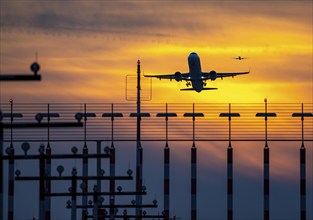 Runway lighting, approach aids, at Düsseldorf International Airport, sunset, aircraft taking off