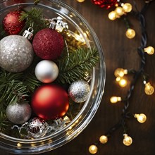 Christmas tree ornaments in a bowl, featuring a mix of glass baubles, pine cones, and fairy lights,