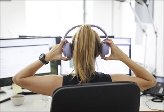 A woman wears headphones in an office in Berlin, 08.08.2024. Working in a call centre